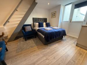 Un dormitorio con una cama y una silla azul. en Carmen Sylva Llandudno G Floor Studio 2, en Llandudno