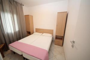a small bedroom with a bed with a pink blanket at Villa Debby appartamento 01 in Rosolina Mare