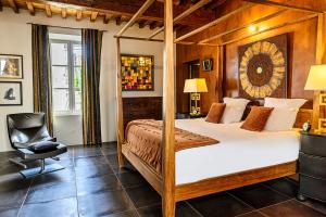 a bedroom with a four poster bed and a chair at Villa Troletti, hôtel particulier de luxe en Provence in L'Isle-sur-la-Sorgue +147 photos