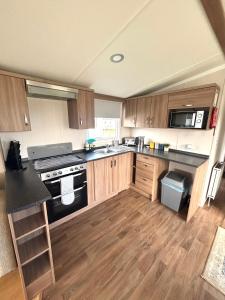 a kitchen with wooden cabinets and a black stove top oven at Seton Sands Holiday Village Klover in Port Seton +7 photos