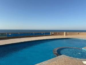 a large swimming pool with the ocean in the background at confort and cozy in Ajman 