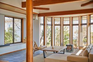 a living room with windows and a couch and a table at プライベートリゾート熱川 in Higashiizu