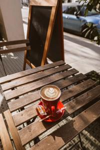 a cup of coffee sitting on a wooden bench at London Visitors Hotel in London