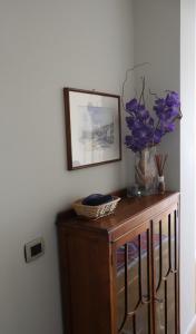 a wooden cabinet with a vase of purple flowers on it at Blue Dream in Portovenere