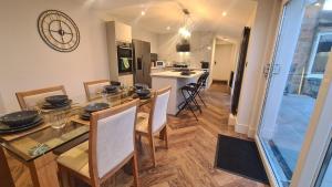 a dining room and kitchen with a glass table and chairs at 5 Bedrooms Sleeps 10 Full Kitchen Parking in Ayr