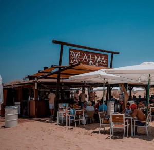 a group of people sitting at tables under umbrellas on the beach at Apartamento en Huelva. in Huelva
