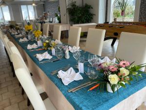 a long table with a blue table cloth and flowers at Auberge du Calvaire in Pontchâteau
