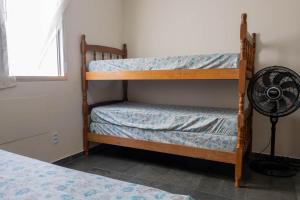 Dos literas en una habitación con ventilador. en Otimo apartamento a 200m do mar com WiFi, en Campo Grande