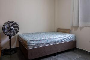 Un dormitorio pequeño con una cama y un ventilador. en Otimo apartamento a 200m do mar com WiFi, en Campo Grande