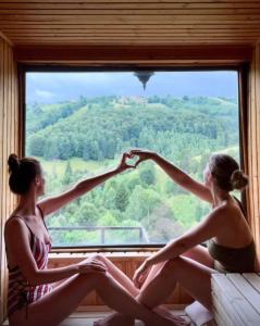 two women sitting on a window sill looking out at Akasha Retreat in Bran