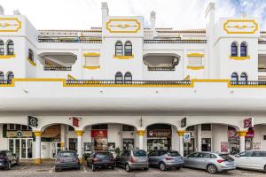 een groot wit gebouw met auto's ervoor geparkeerd bij Côte et mer - BY BEDZY in Carvoeiro