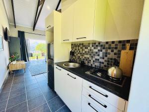 una cucina con mobili bianchi e un lavandino di Mountain View Cottage a Wildernis