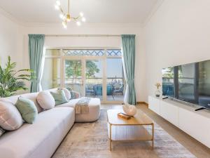Una sala de estar con un sofá blanco y un televisor. en Beachfront Sea View 1BR-Jash Falqa- Palm Jumeirah, en Dubái