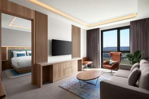 ein Wohnzimmer mit einer Couch, einem Fernseher und einem Bett in der Unterkunft Courtyard by Marriott Dakar Diamniadio in Dakar