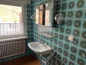 a blue tiled bathroom with a sink and a mirror at Ferienwohnung mit 4 Betten - Balkon - Küche in Fuldabrück +21 photos