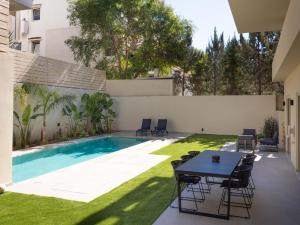 a patio with a table and chairs next to a swimming pool at The Samirah Luxury Residences in Elliniko in Athens