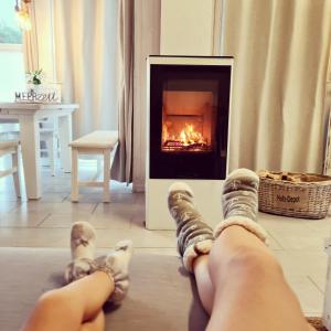 a person with their feet up in front of a fireplace at Strandhaus Rügen 243 - Meerblick, Sauna, Kamin & Whirlpool in Baabe