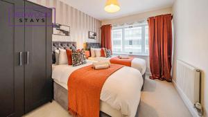 - 2 lits dans une chambre avec des rideaux orange dans l'établissement Premium Serviced Apartment in Basingstoke Town Centre, Free Parking By Redwood Stays, à Basingstoke