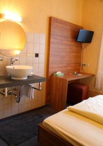 een badkamer met een wastafel, een bed en een spiegel bij Zur Lindenau in Rüdesheim am Rhein
