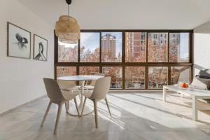 - une salle à manger avec une table, des chaises et de grandes fenêtres dans l'établissement New Apartments Benidorm beach & city, à Benidorm