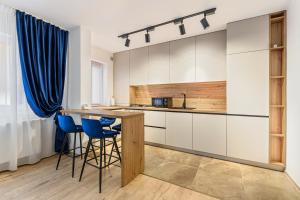 a kitchen with white cabinets and blue bar stools at Blue Moon Apartments in Braşov