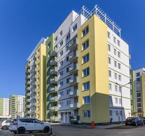 a tall apartment building with cars parked in a parking lot at Blue Moon Apartments in Braşov