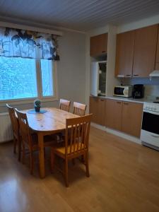 a kitchen with a wooden table and chairs in a room at Tuulanmajoitus in Mänttä
