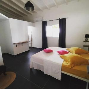 a bedroom with a bed with yellow and red pillows at Villa moderne avec piscine à Sainte-Rose, 160 m² in Sainte-Rose