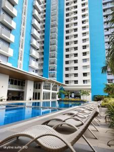 a swimming pool with chaise lounge chairs in front of buildings at ManTa Vibe at Mesavirre Garden Residences in Bacolod