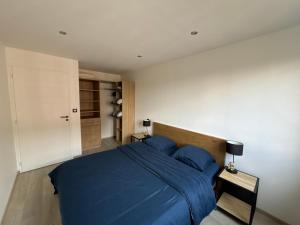 a bedroom with a blue bed and a white wall at Appartement de Adrien Garage privé in Charleville-Mézières