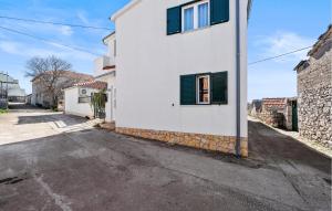 a white house with green shutters on a street at 2 Bedroom Gorgeous Apartment In Vezac in Vezac