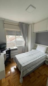 a bedroom with a bed and a desk and a window at Apto Charmoso Próximo à Catedral in Santa Cruz do Sul