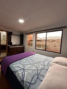 une chambre avec un grand lit et deux fenêtres dans l'établissement Departamento Familiar Cómodo Cerca de el Centro, à Cuenca