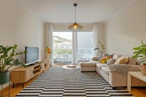 ein Wohnzimmer mit Sofa und Fernseher in der Unterkunft Refúgio Girassol in Caniço