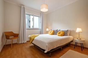 ein Schlafzimmer mit einem Bett mit zwei Kissen und einem Fenster in der Unterkunft Refúgio Girassol in Caniço