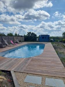 a swimming pool on a wooden deck with chairs around it at Petite maison bretonne 2 personnes accès piscine in Erquy
