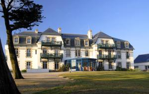 un gran edificio blanco con ventanas y balcones. en Résidence Odalys Valentin plage, en Batz-sur-Mer