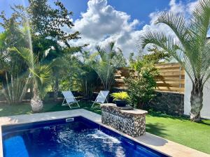 a swimming pool in a yard with palm trees at Villa Tropéa in Les Cocos
