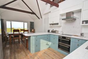 eine Küche mit blauen Schränken und einem Esstisch in der Unterkunft ON THE BEACH holiday home in Saint Merryn