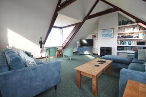 ein Wohnzimmer mit blauen Sofas und einem Tisch in der Unterkunft ON THE BEACH holiday home in Saint Merryn