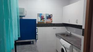 Una pequeña cocina blanca con fregadero y encimera. en Apartamento Pacífico, en Chipiona