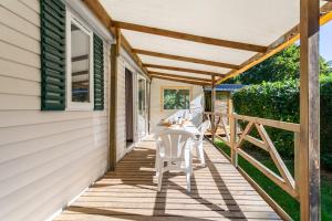 a porch with a white chair on the side of a house at Camping Paradis Le Giessen in Bassemberg