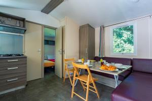 a living room with a table and a purple couch at Camping Paradis Le Giessen in Bassemberg +10 photos