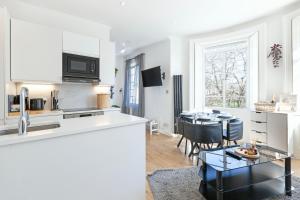 a kitchen and living room with a table and chairs at Luxury 2 Bedroom Flat In Royal Crescent in London