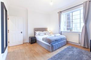 a bedroom with a bed and a large window at Luxury 2 Bedroom Flat In Royal Crescent in London