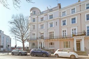 two cars parked in front of a large building at Luxury 2 Bedroom Flat In Royal Crescent in London