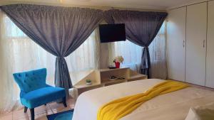 a bedroom with a bed and a blue chair and window at ekhaya guesthouse in Secunda