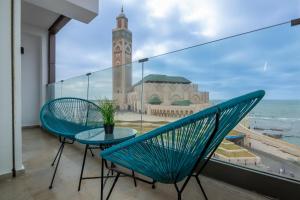 a balcony with two chairs and a table and a clock tower at TCE Bel Azur Residency - Ocean & Hassan II View in Casablanca-Port