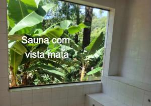 a bathroom window with a view of a banana tree at Pousada do Rodrigo in Macacos +124 photos