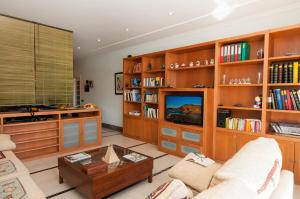a living room with wooden book shelves and a tv at Sonnenland House for 12 by VillaGranCanaria in Maspalomas